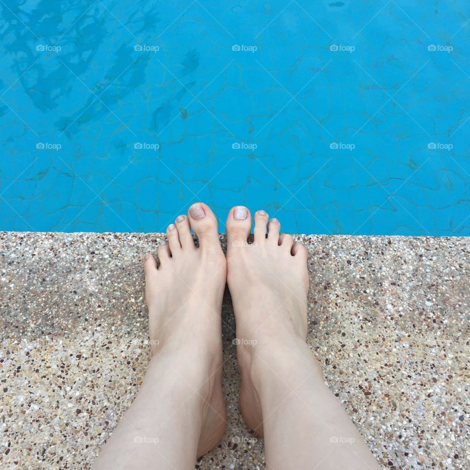 View of bare female feet at swimming pool side great for any use.