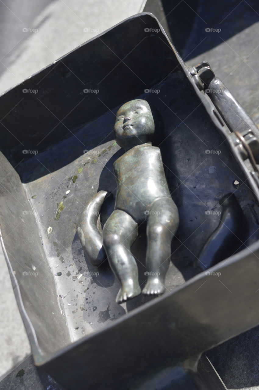 Eine Metallpuppe mit abgetrennten Armen liegt in einem Metallkoffer.