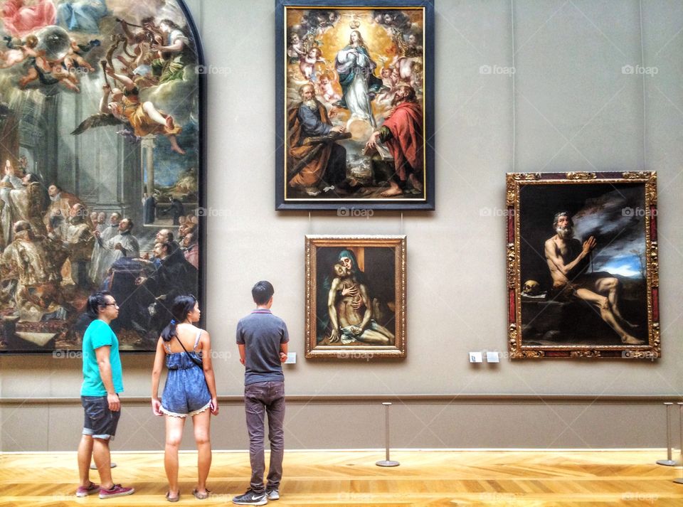 at Louvre museum . three people in front of paintings in the louvre museum 