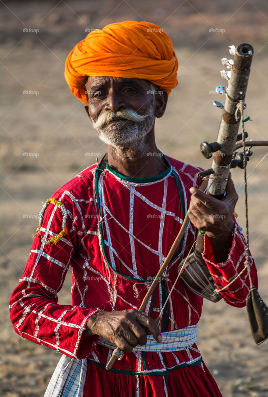 An old gypsy man playing a musical instrument called 'Sarangi' in Pushkar, Rajasthan, India