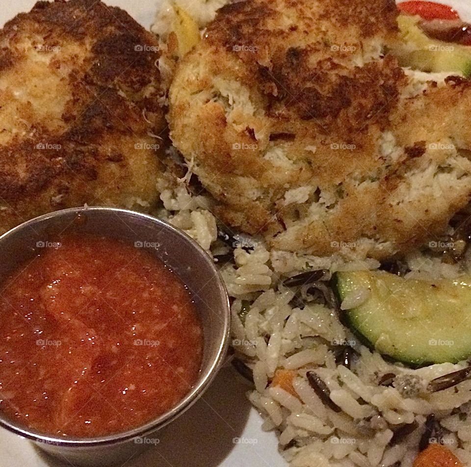 Crab cakes over wild rice with cocktail sauce