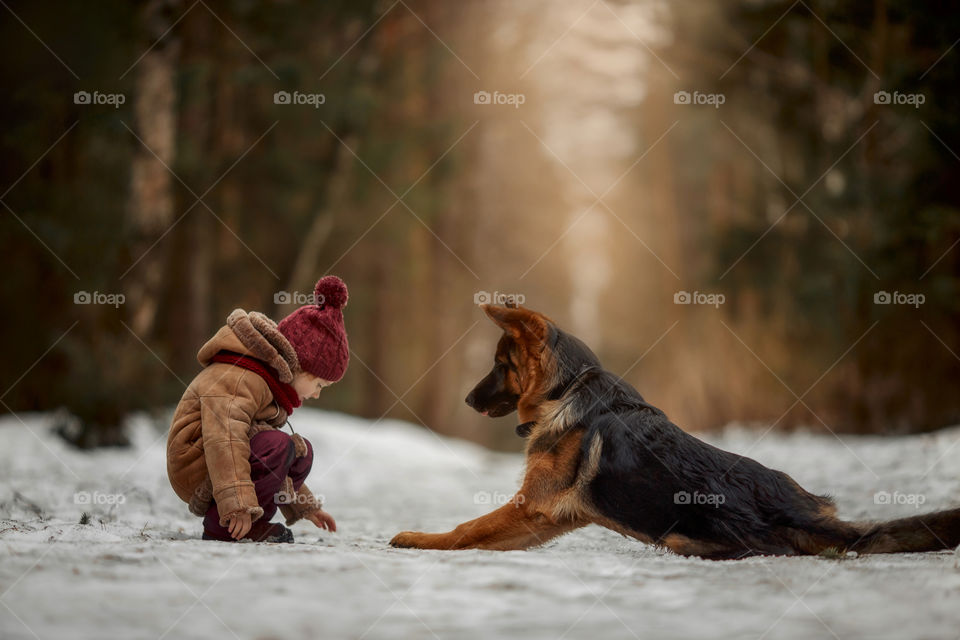 Little girl with German shepherd 6-th months puppy at early spring forest