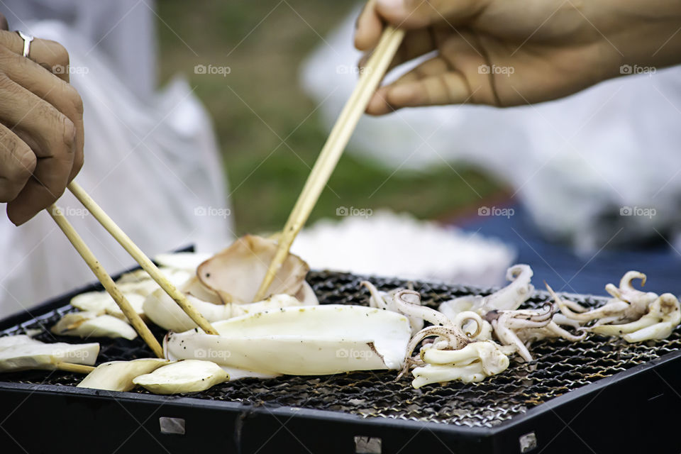 Fresh squid and mushrooms on the grill grate steel.