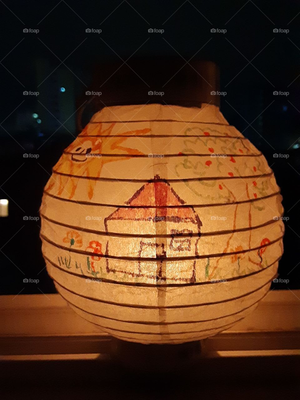 a wishing balloon. a little boy made it and draw a simple home with tree, flowers and a smiling bright sun. it means that he wants a simple but a happy family life. i put lights inside and it looks so beautiful for the drawing looks so clear.