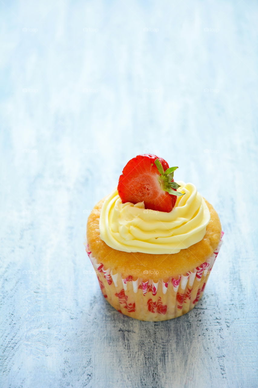 Cupcake with strawberry. Cupcake with strawberry on blue wooden background