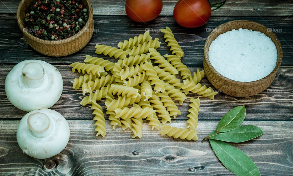 Raw pasta with ingredients and wooden accessories