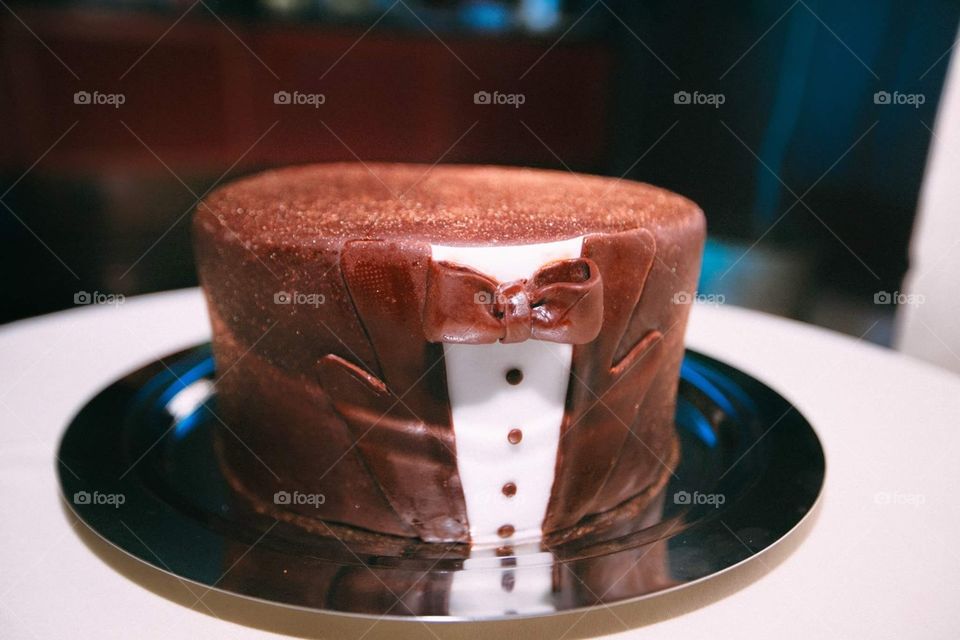 A cute minimalist chocolate wedding cake decorated as a groom's suit