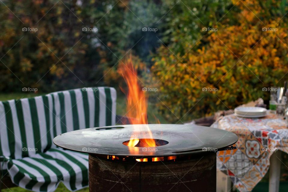 A red flame burns from a fire pit in autumn