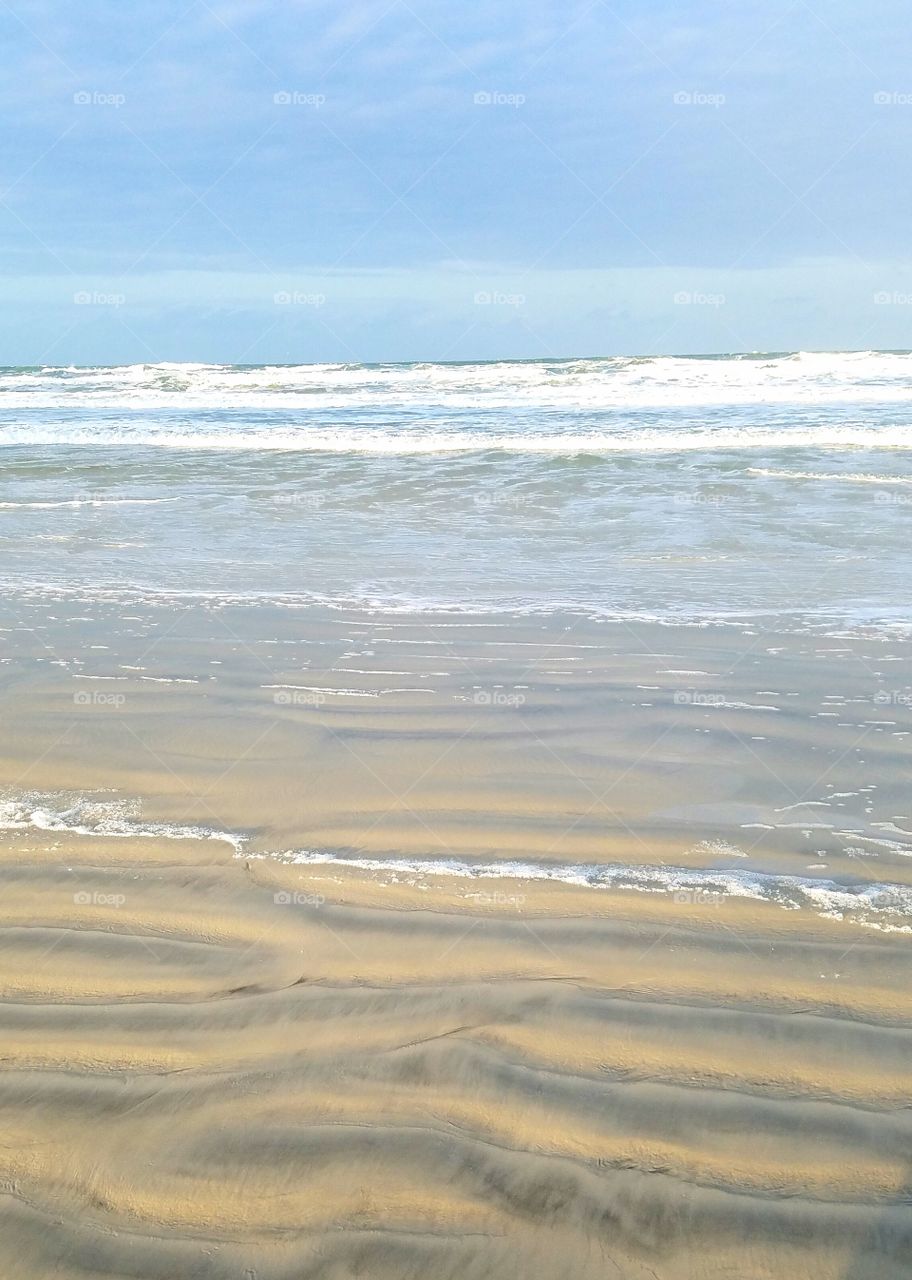 patterns on the beach.  from the sky to ocean to beach.  all rippling.