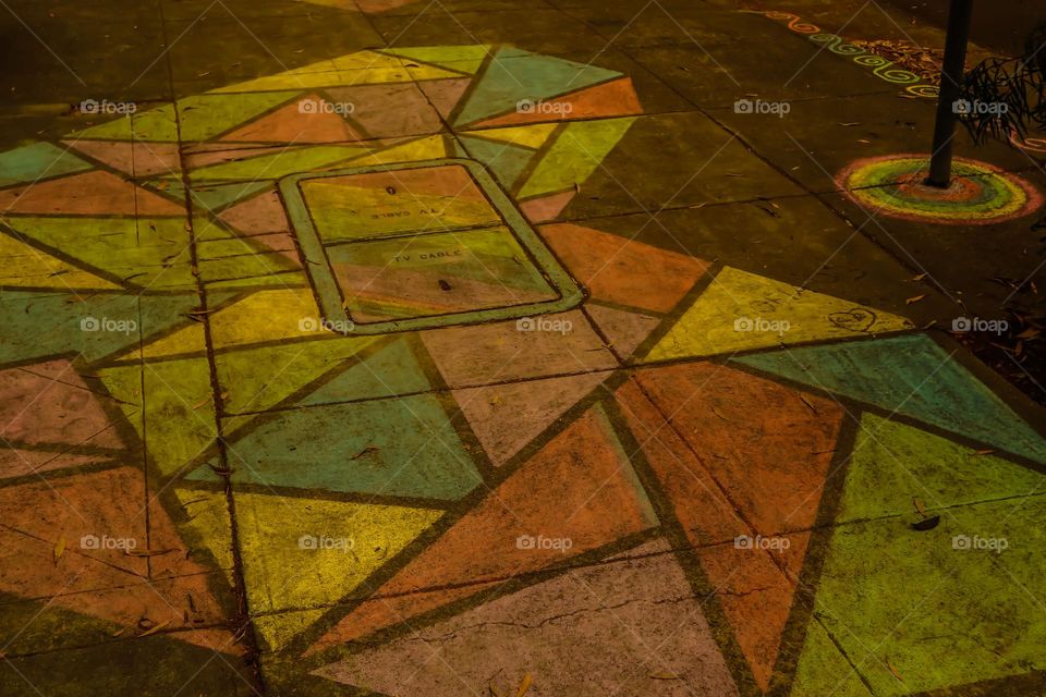 Chalk sidewalk drawing in the shape of a heart comprised of multi colored triangles 