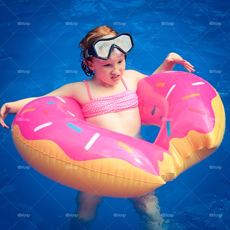 Child on inflatable in swimming pool enjoying summer vacation.