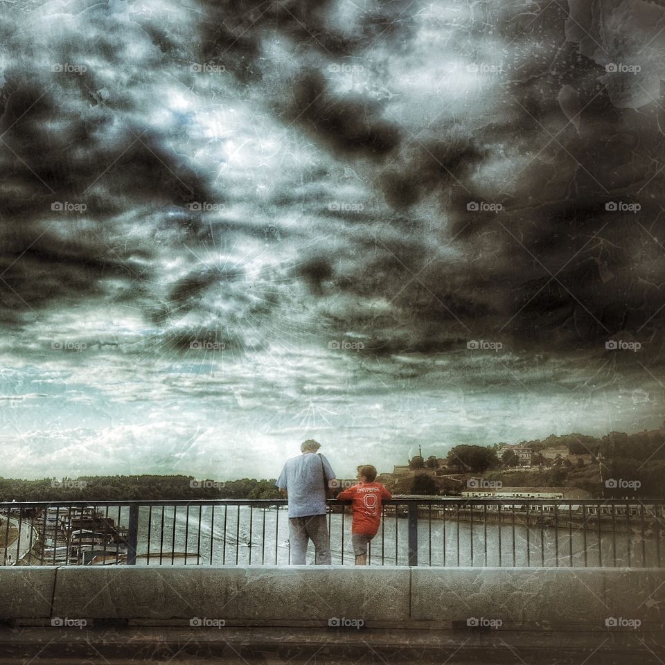 Father and son on bridge. This photo is taken with an iPhone in Belgrade. Belgrade is capital city of Serbia. Father and son talking on storm.