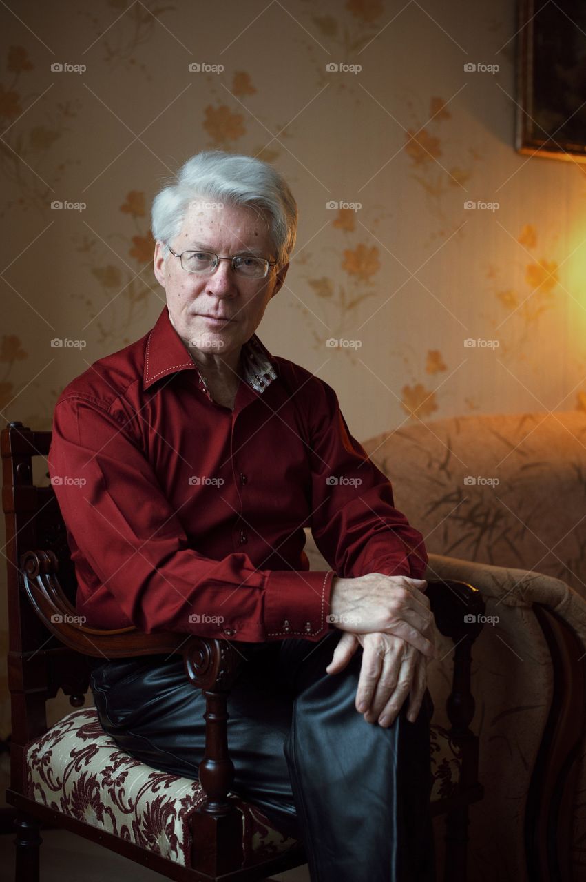 Retired old man sitting on chair in home