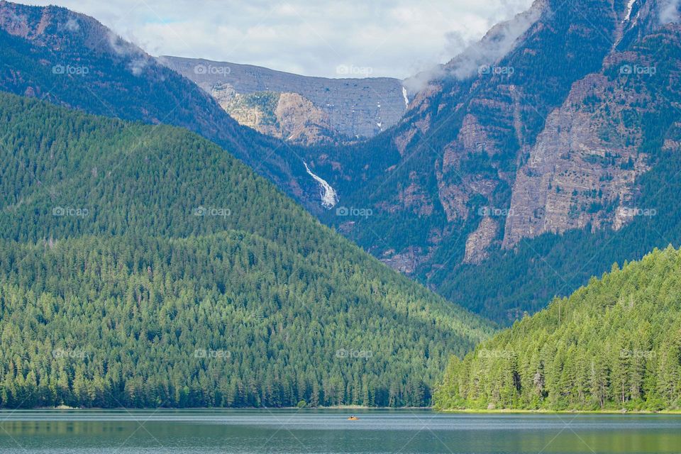 A heavily forested area and a large waterfall create the background for a lovely reservoir in Montana