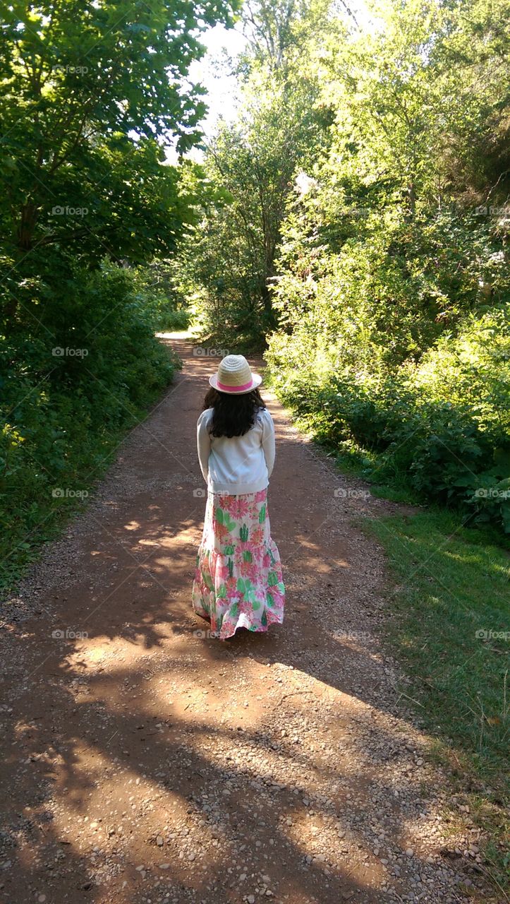 Girl wearing hat and flower skirt posing on forest trail