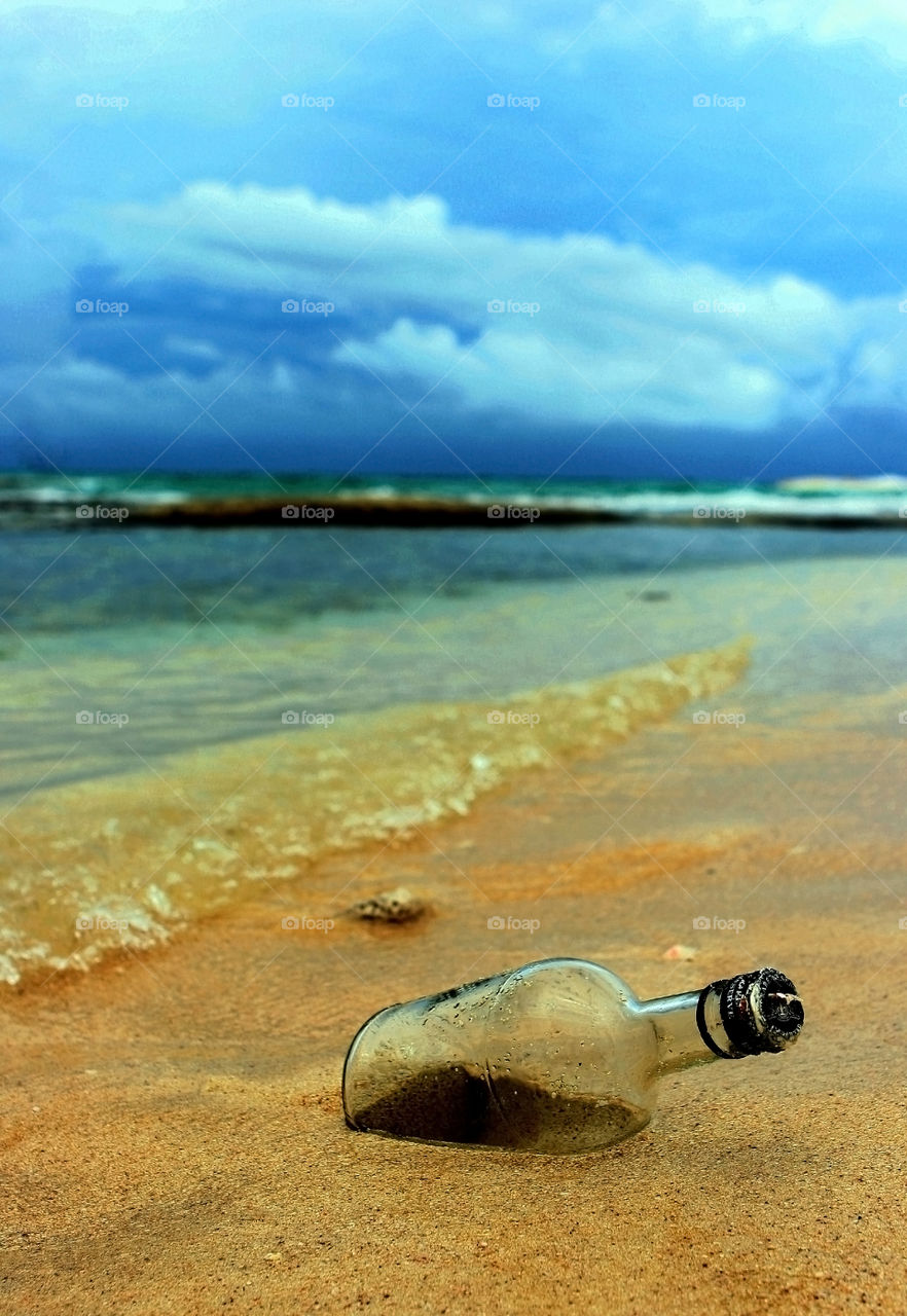 message in the bottle . empty bottle found on the beach in stormy tropical afternoon 