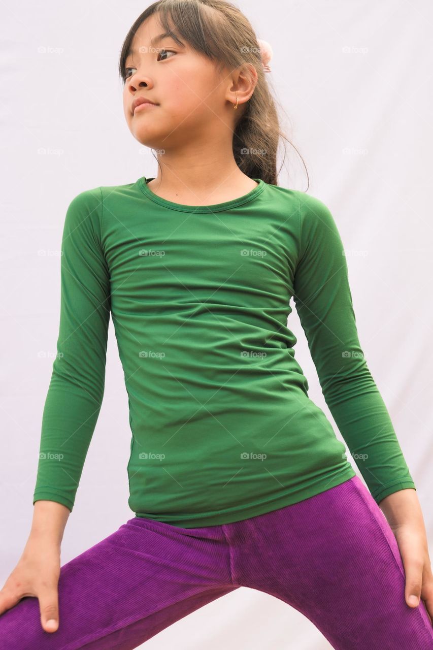 A young little girl striking a pose in her casual clothing with complementary colors.
