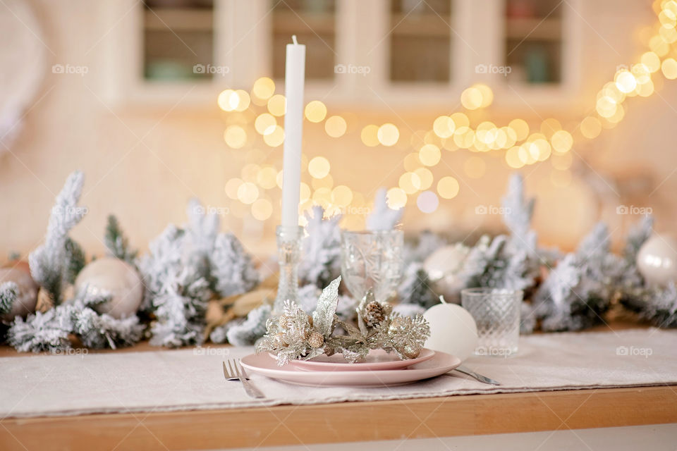 Festive winter cozy kitchen interior with garlands, decorations and gifts.  Christmas dinner at the decorated table.