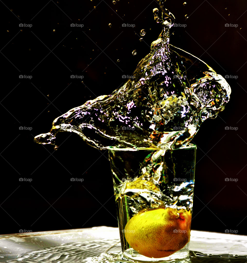 Lemon splashing in the glass of water