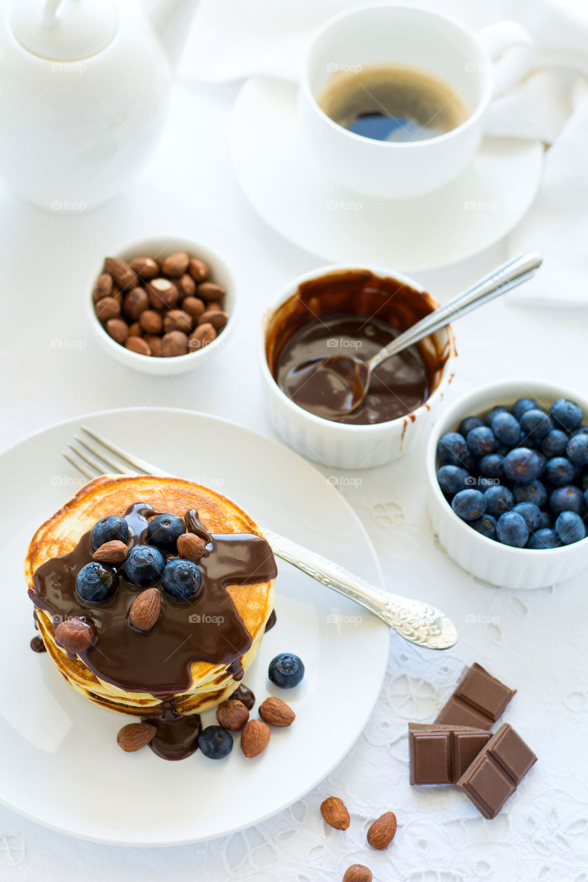 Stack of pancakes with chocolate sauce, blueberry and nuts. Healthy breakfast concept