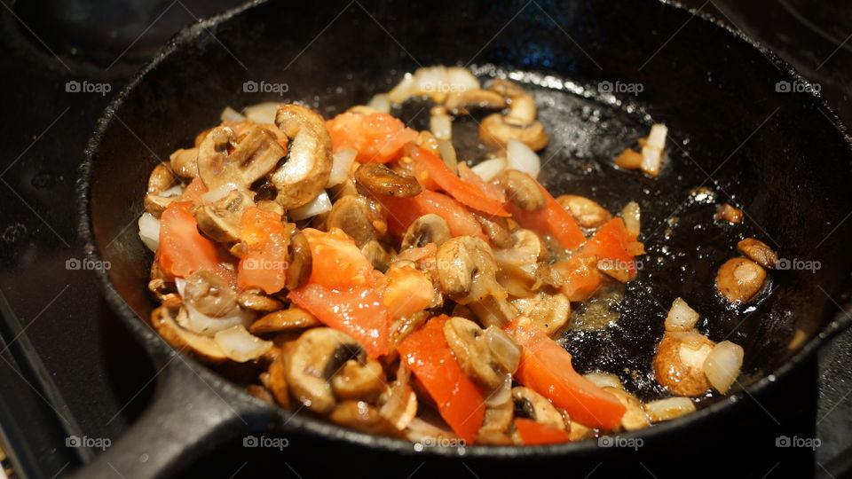 Iron fry pan with onions, tomatoes and mushrooms.