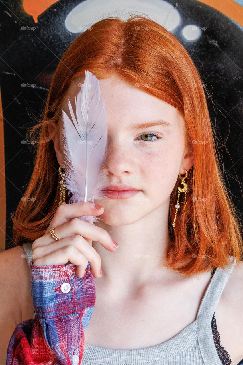 Creative photography, light and posisjon, red hair ,lighter than before ,with a feather in her hand .