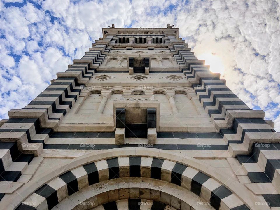 Bottom up view to Basilique Notr-Dame de la Garde tall tower beautiful architectural details against bright cloudy sky 