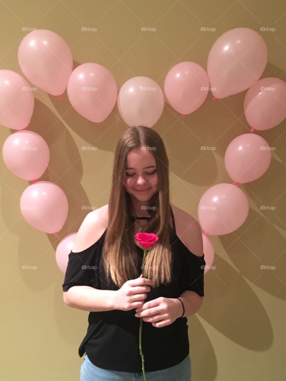 Beautiful girl looking at a rose with a heart balloon background