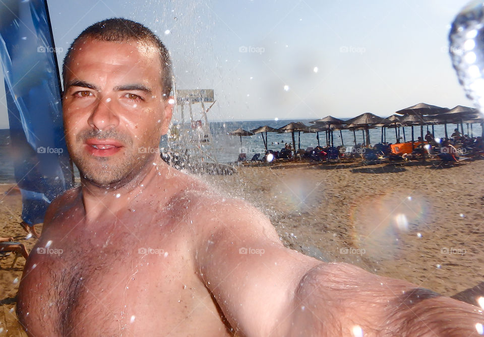 male under the shower on the beach