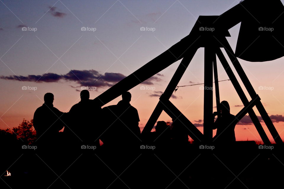 College men surround a trebuchet to launch pumpkins