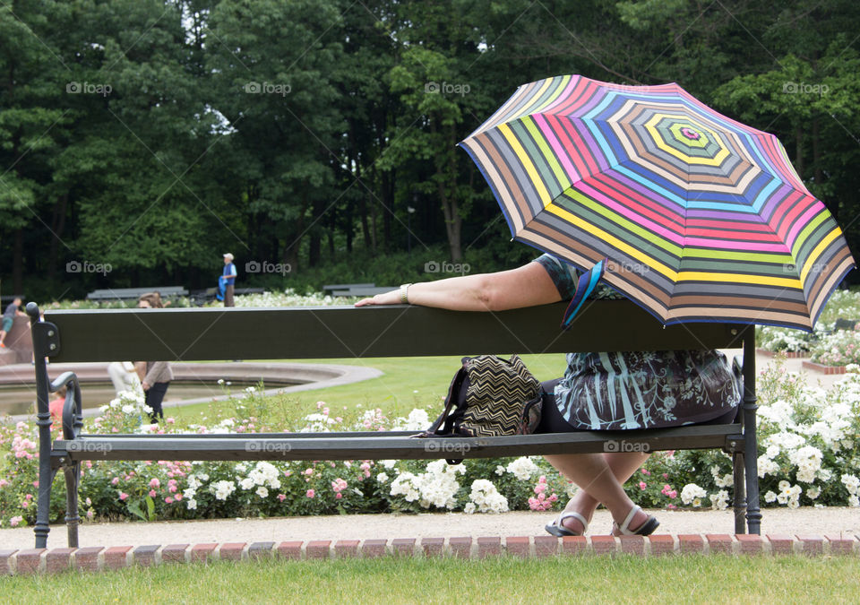 Elderly lady sitting on a bench in the park and watching the world go by