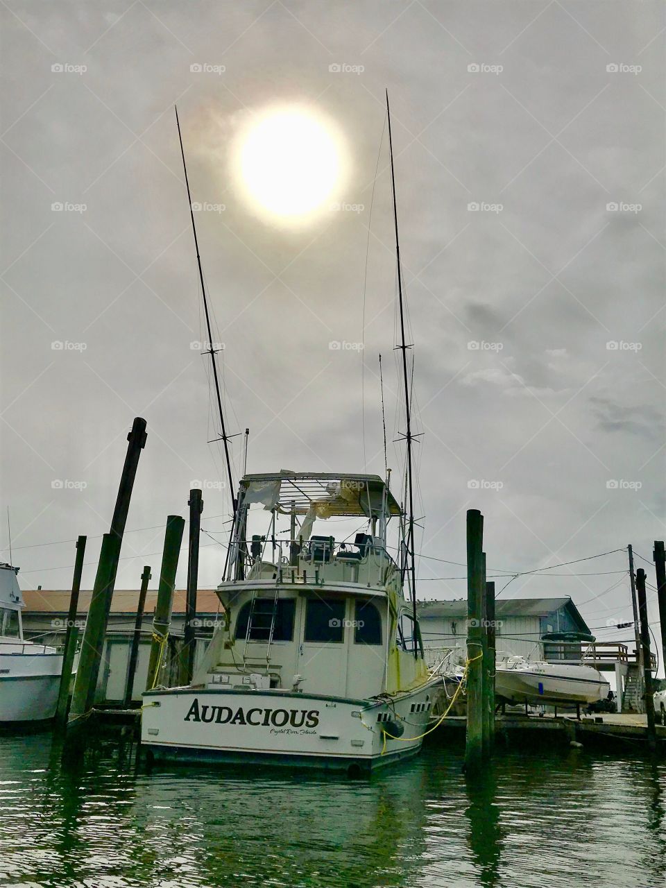 Sun caught between 2 fishing poles on a fishing boat. 