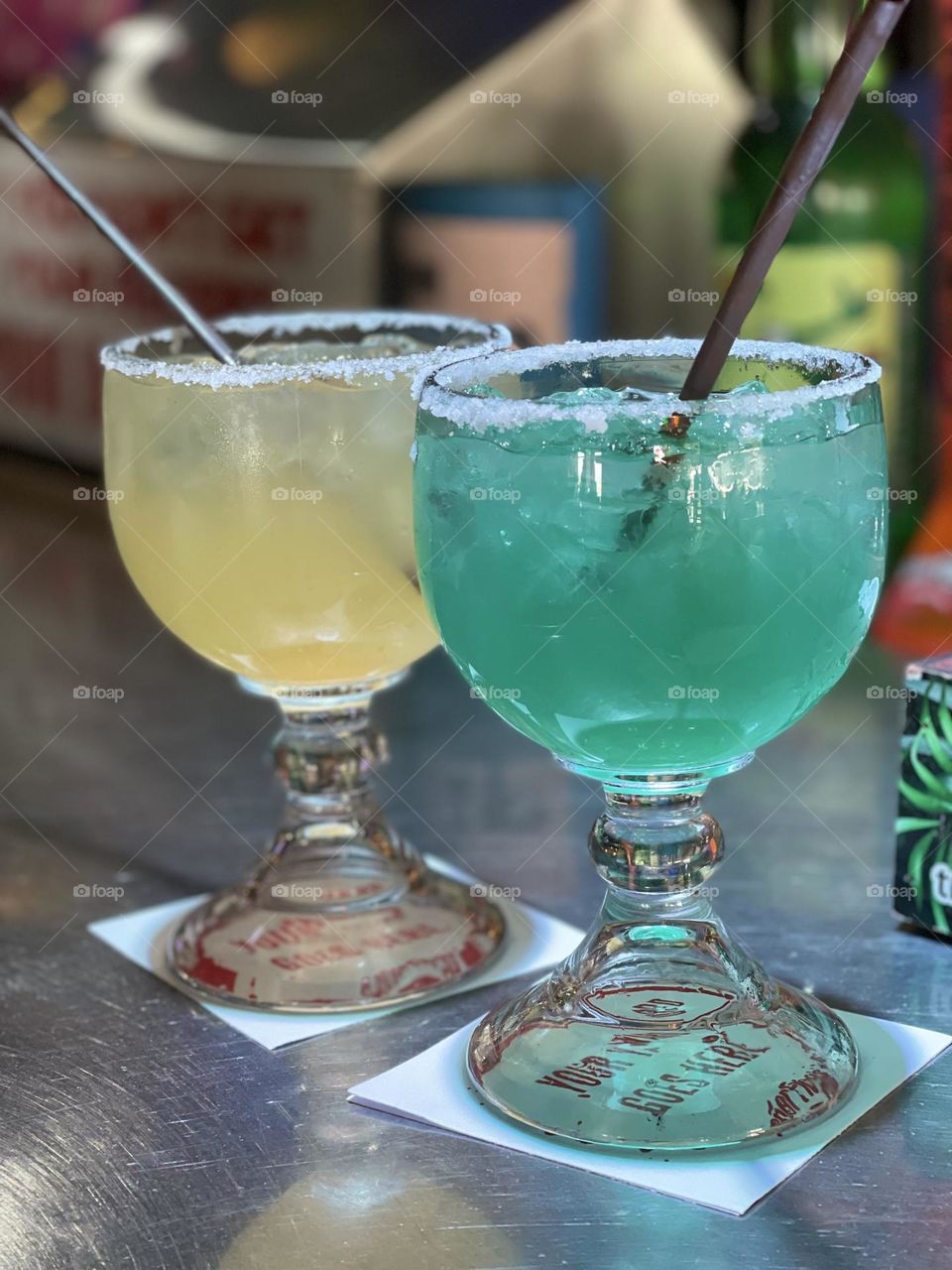 Delicious cocktails are ready to be sipped. The sweet drinks have salt on the rims that shows off the vibrate colors of the margaritas.