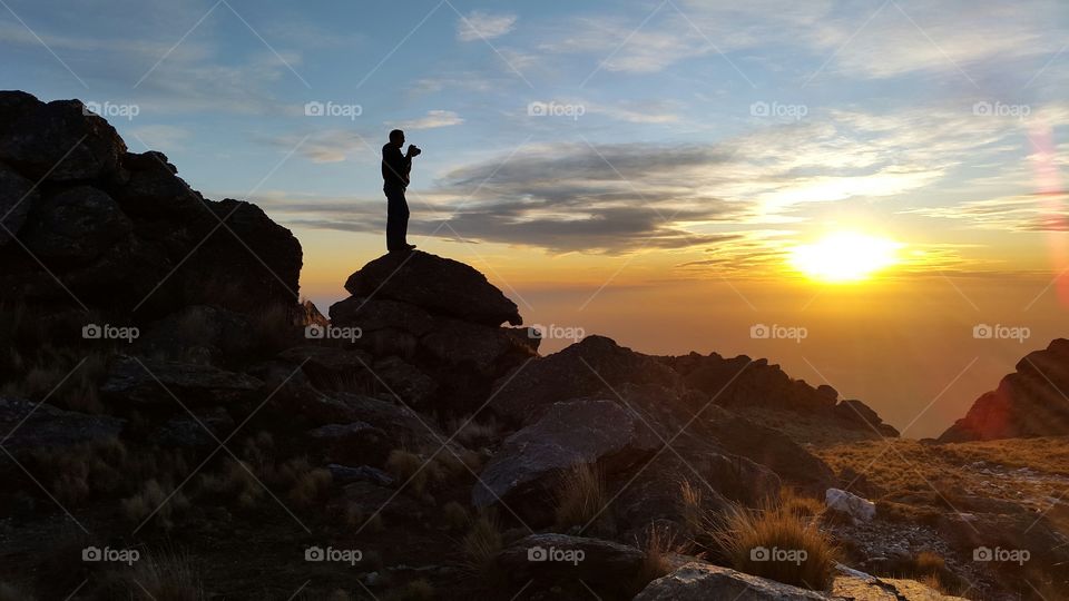 Silhouette of a person standing on rock for photography