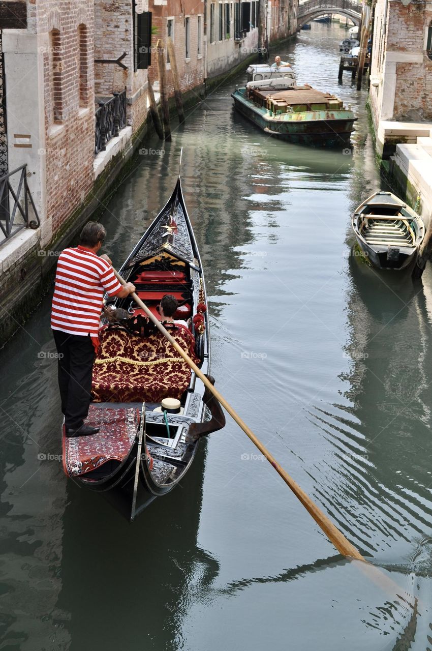 Venetian gondolier leads a gondola along one of the canals in Venice