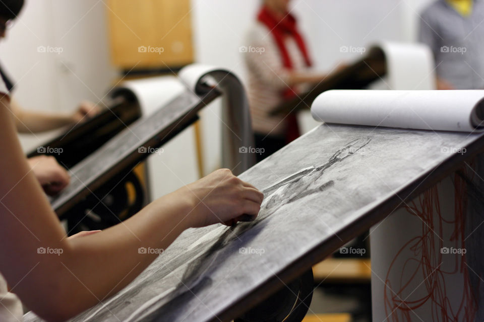 An artist sketches a model in charcoal in the studio