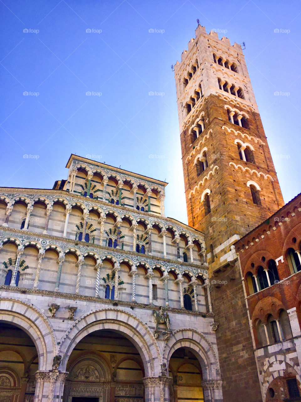 Italian marble church facade with sun glow behind the tower