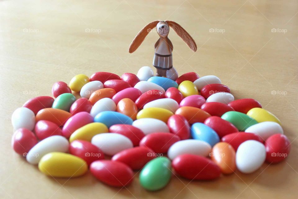 Happy Easter! Bunny with colorful sugar eggs on a wooden table