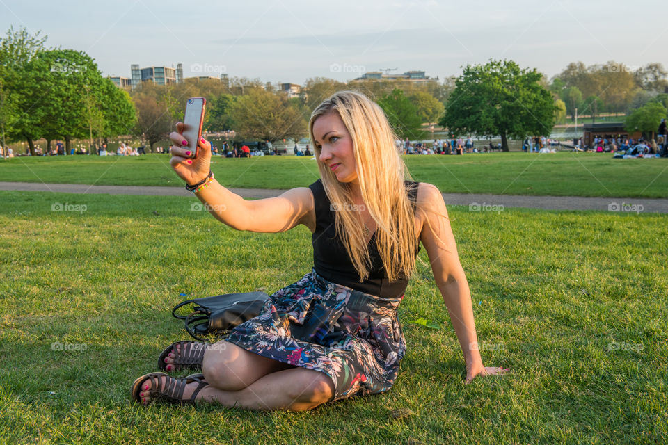 Woman tourist from Sweden 30 years plus taking a selfie in Hyde park in London.