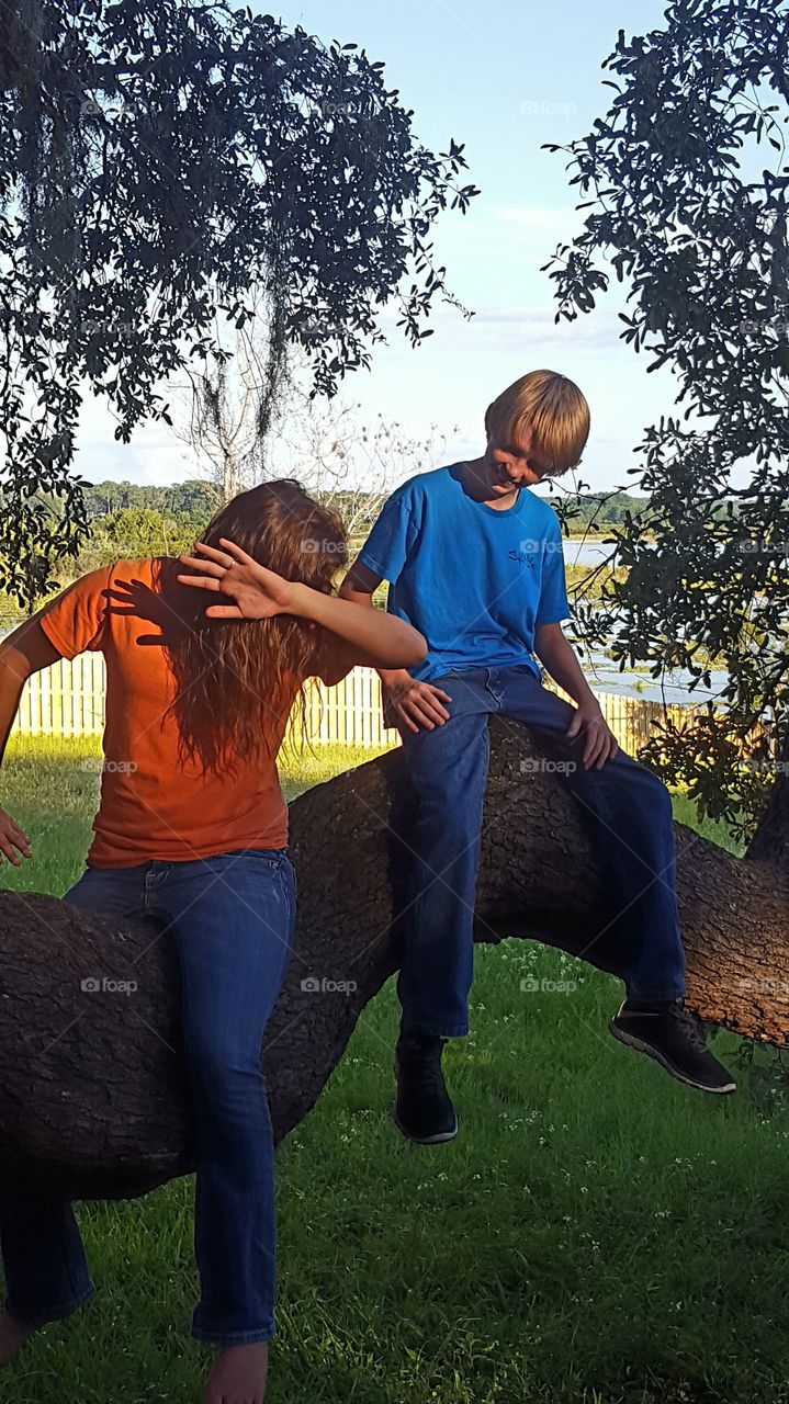 Teenagers sitting on tree trunk