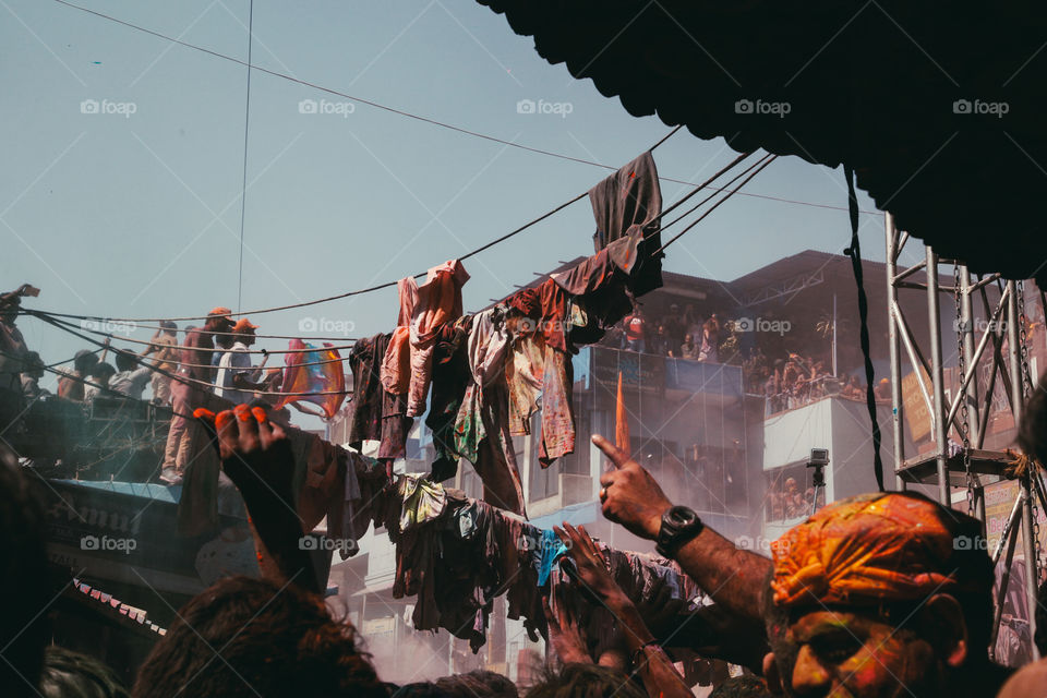 People throw clothes and colourful powder in a crowded square during Holi festival in Pushkar, India.