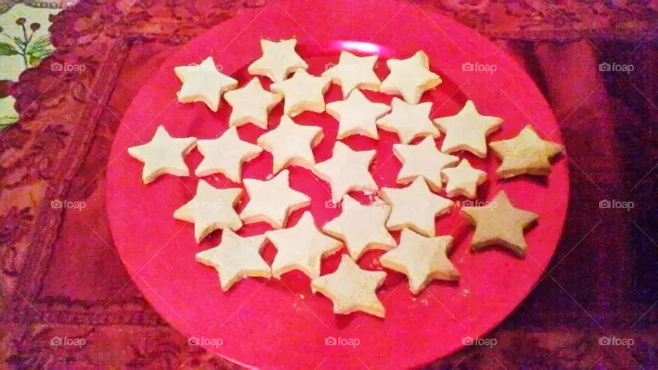 Some star-shaped cookies covered with powdered sugar in a red plate