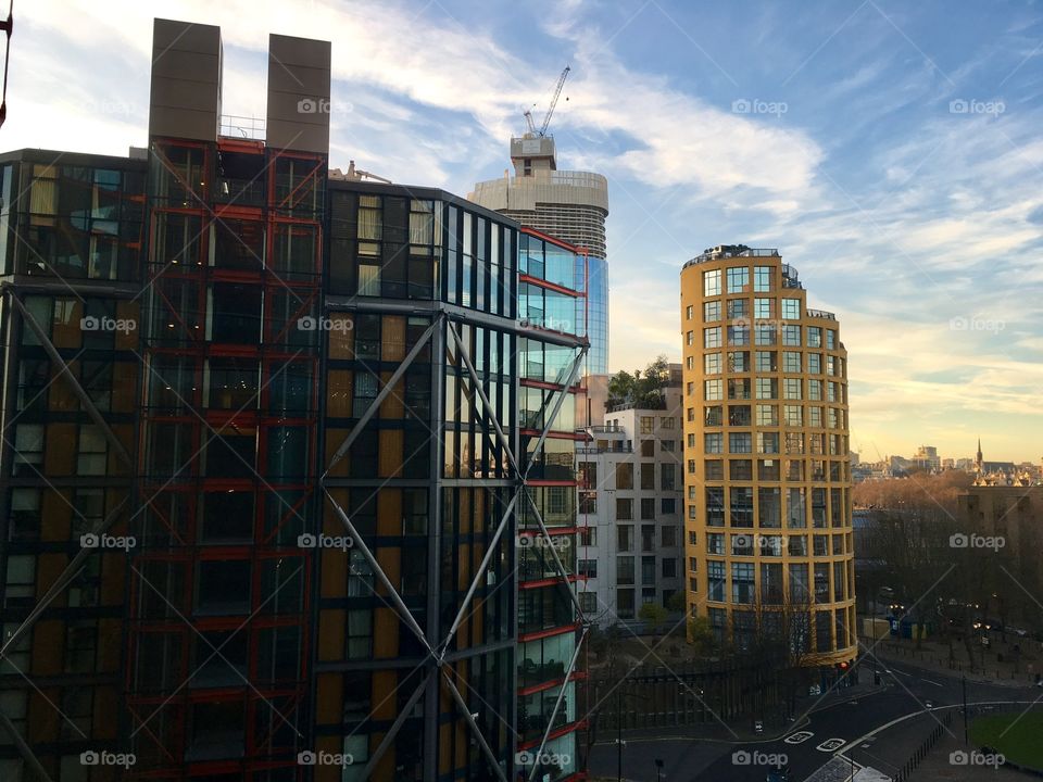 Futuristic architecture in London: a yellow cylindrical building and another made of mostly glass. 