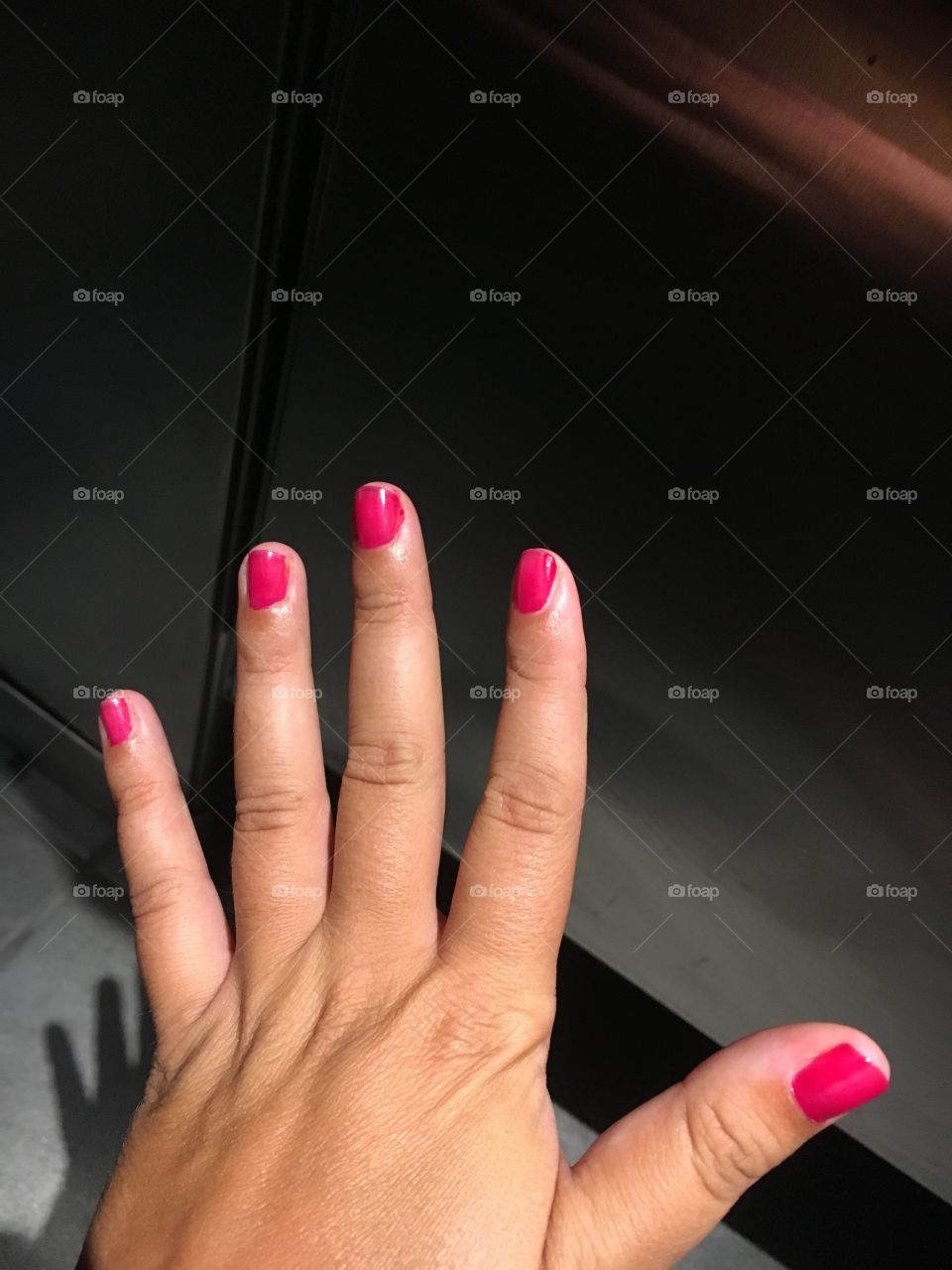 Hand with bright pink painted nails 