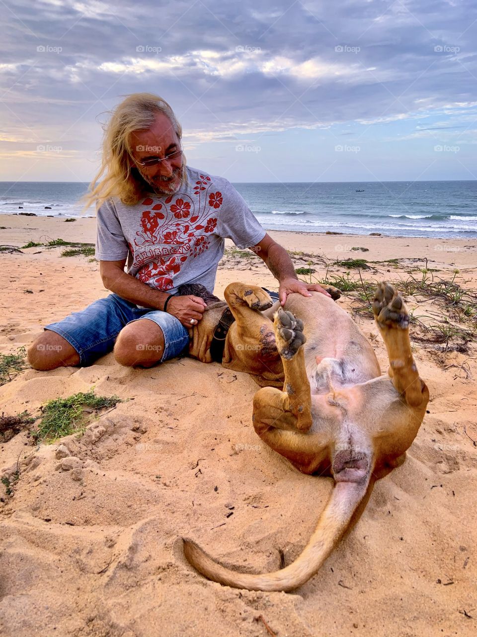 Man cuddling his dog in the beach 