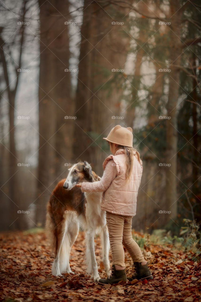 Cute smiling girl with borzoi dog in an autumn park 