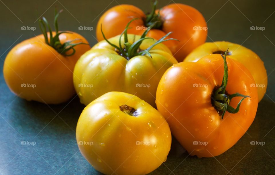 Freshly picked yellow and orange tomatoes on green counter in natural light 