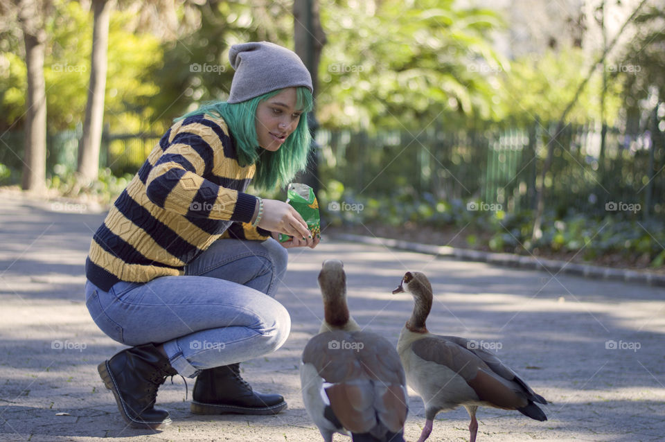 Alternative girl feeding Egyptian geese cute birds green hair