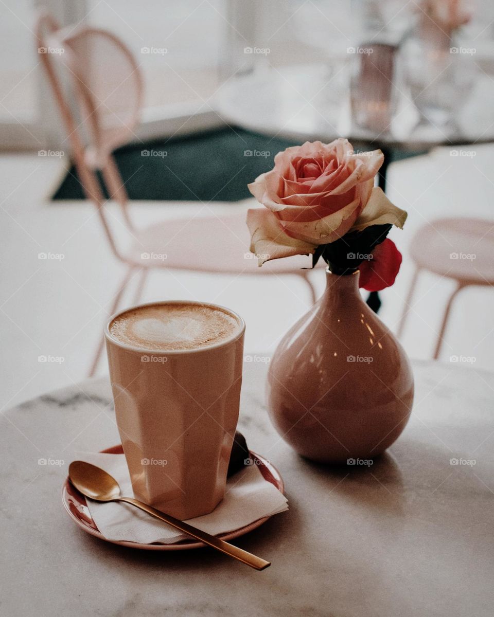 Coffee on the table in a cosy café, pink coffee cup