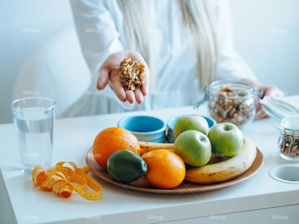 Young beautiful woman in white clothes  with Long blond hair taking nuts in hands, nutrition concept